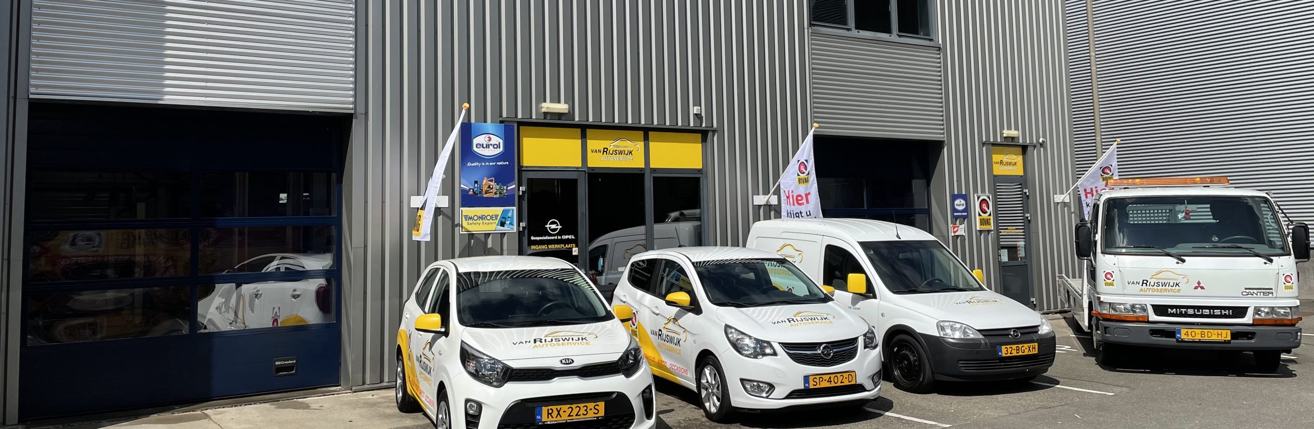 Het pand van Van Rijswijk Autoservice aan de Eerste Tochtweg, met de bedrijfswagens en de gele gevelbelettering