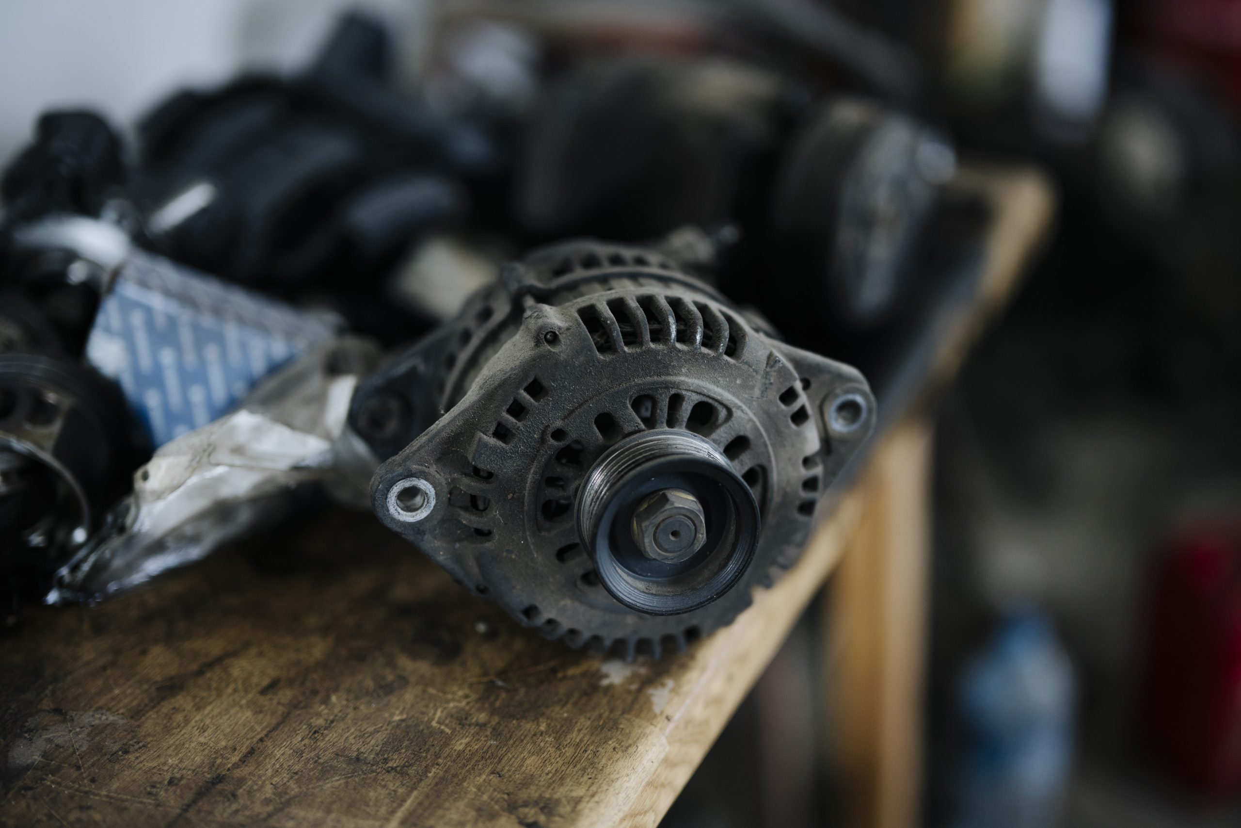 Een dynamo op een houten werkbank, met andere auto-onderdelen eromheen
